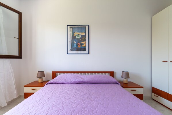 A bedroom with a bed, two bedside tables with lamps, a wardrobe, and a framed picture on the wall.
