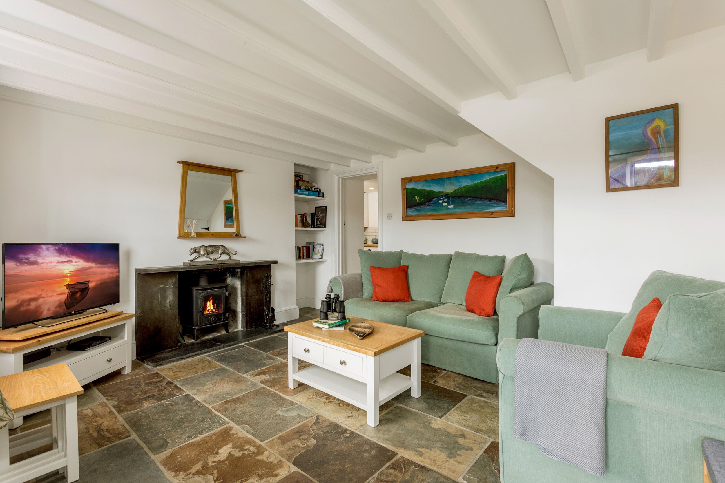 A living room with a fireplace, green sofa, and a television.