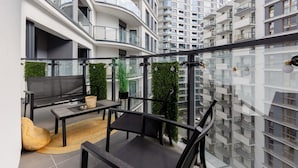 Een modern appartement met een balkon, gemeubileerd met een bank, stoelen en een kleine tafel.