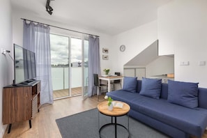 Una sala de estar moderna con un sofá, una mesa de centro, un televisor y un balcón con cortinas.
