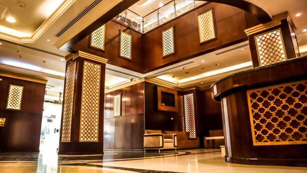 A spacious lobby with a high ceiling, wooden paneling, and a central seating area. - Almukhtar Aldahbe (Madinah)