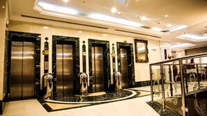 A hotel lobby with a marble floor, four elevators, and a glass railing. - Almukhtar Aldahbe (Madinah)
