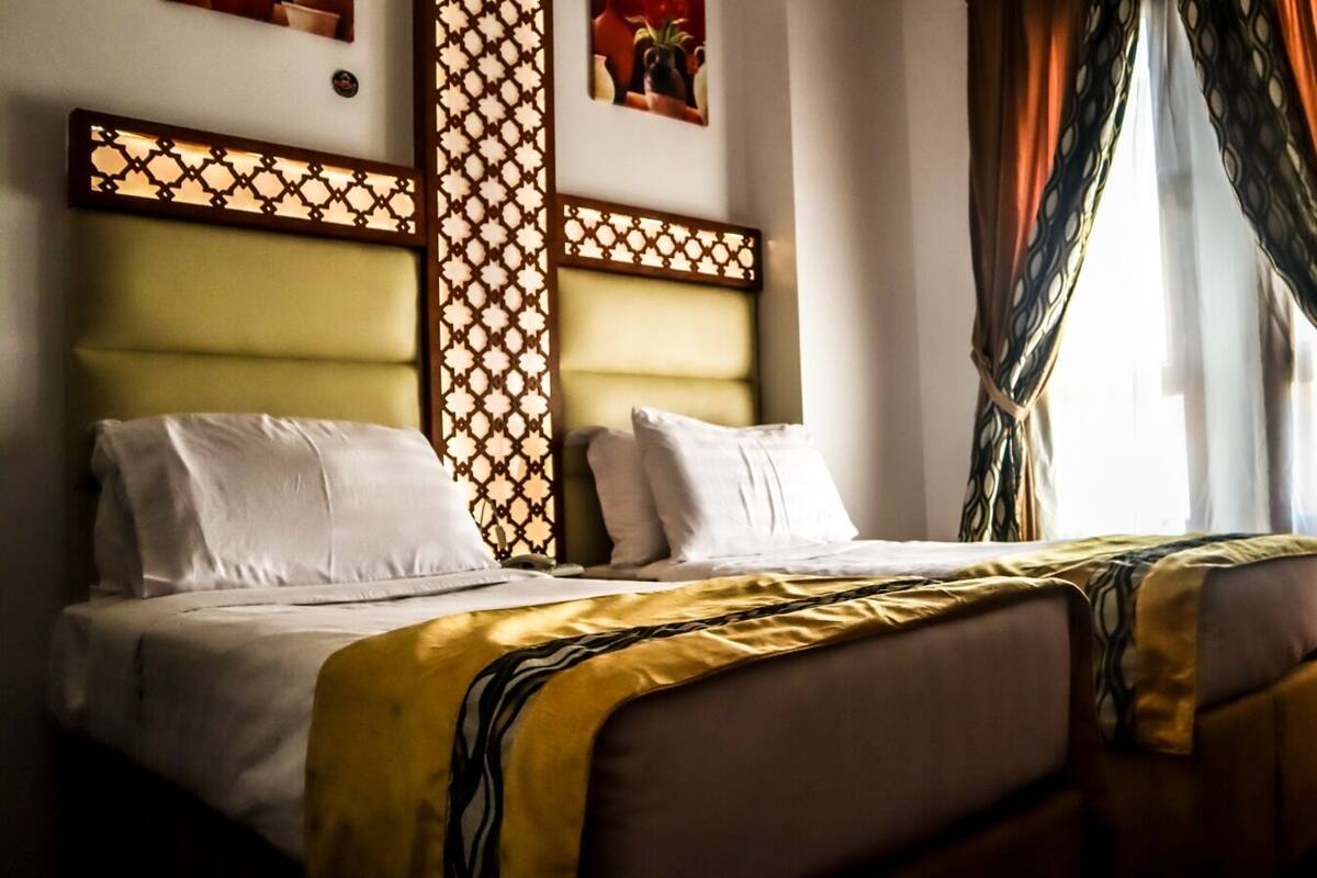 A double bed with a yellow and black striped blanket, white pillows, and a wooden headboard with a lattice design.