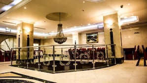 A spacious lobby with a central seating area, a chandelier, and a large painting on the wall. - Almukhtar Aldahbe (Madinah)