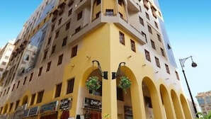 A multi-story building with a yellow facade, multiple balconies, and arched windows. - Almukhtar Aldahbe (Madinah)