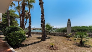 A landscaped outdoor area with palm trees, a small bush, and a signboard. - 3563 Villa del Bacino - App Rosso by Barbarhouse (Porto Cesareo)