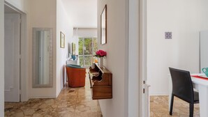 A hallway with a wooden bench, a small table with a vase of flowers, and a white door on the left. - 3563 Villa del Bacino - App Rosso by Barbarhouse (Porto Cesareo)