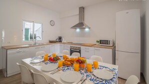 Cucina moderna con mobili bianchi, una cappa in acciaio inossidabile e un forno a microonde.
