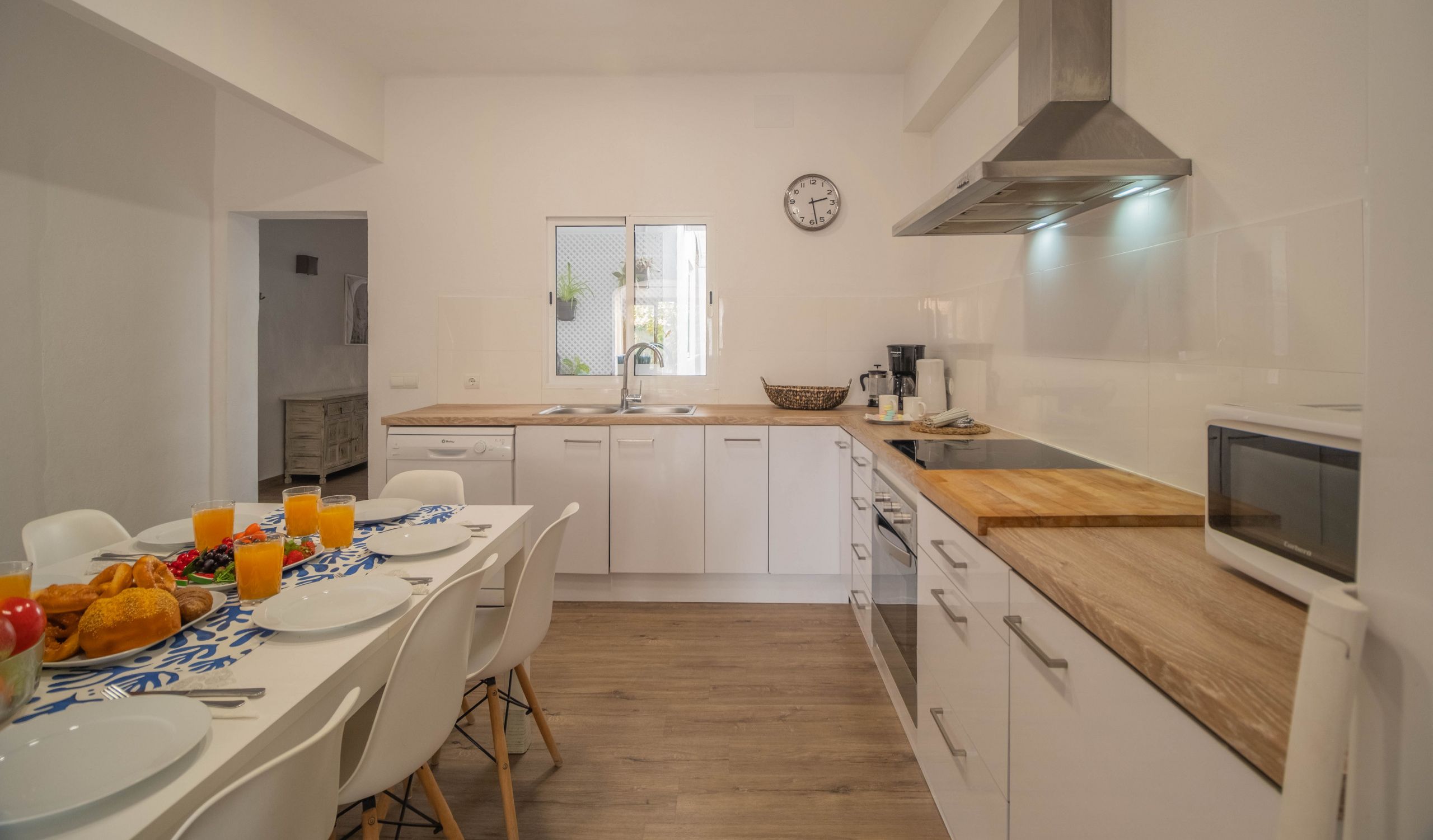 Une cuisine moderne avec des meubles blancs, un plan de travail en bois et un four encastré.