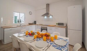 A modern kitchen with white cabinets, a stainless steel range hood, and a microwave.