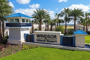 A sign for Windsor Island Resort with a pool area, palm trees, and a building with a blue roof. - Sleeps 17! Windsor Island 7BR w/ Private Pool (Davenport)