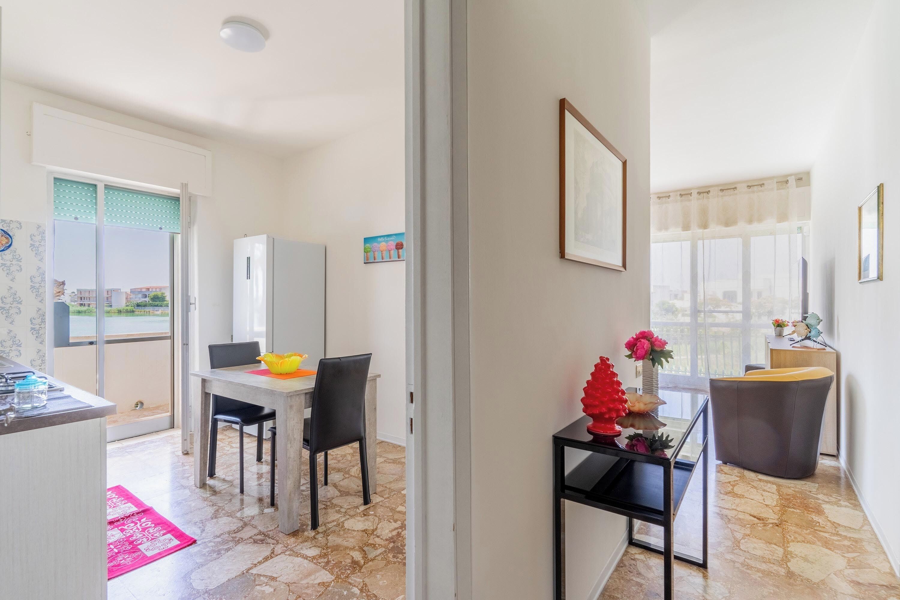 A modern kitchen with a dining area, a refrigerator, and a window with a view.
