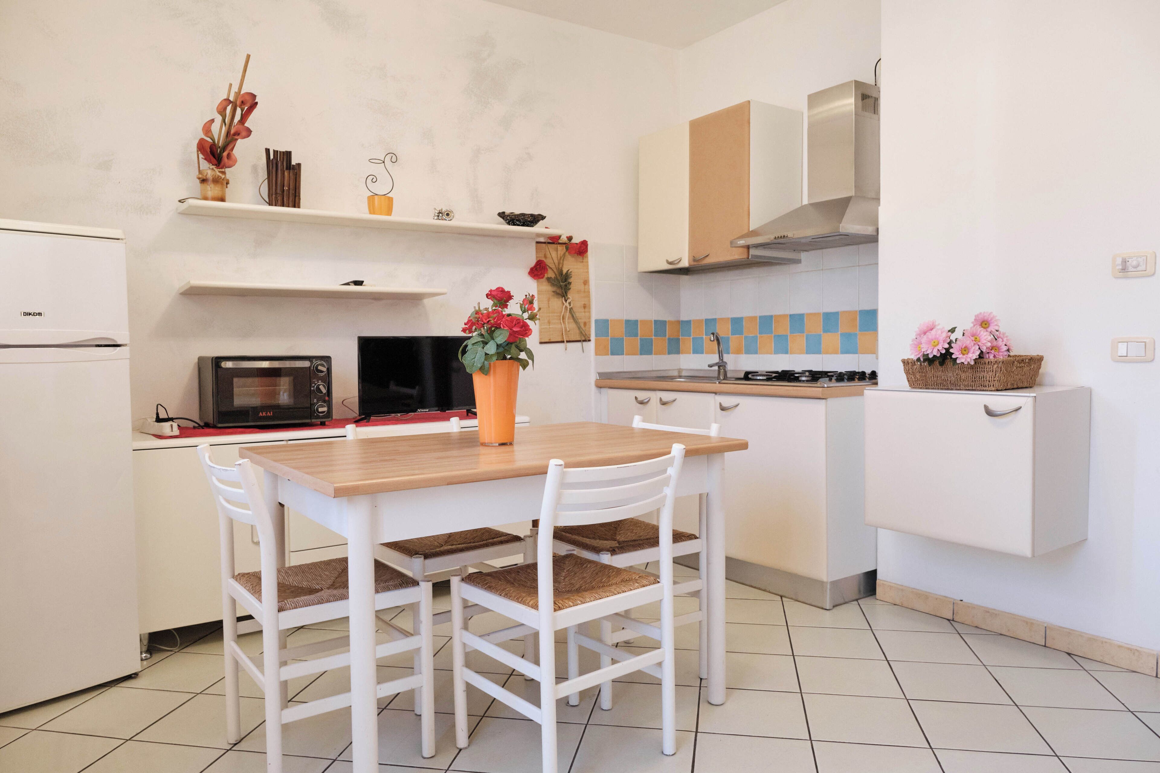 A kitchen with white cabinets, a microwave, a stove, and a dining table with chairs.