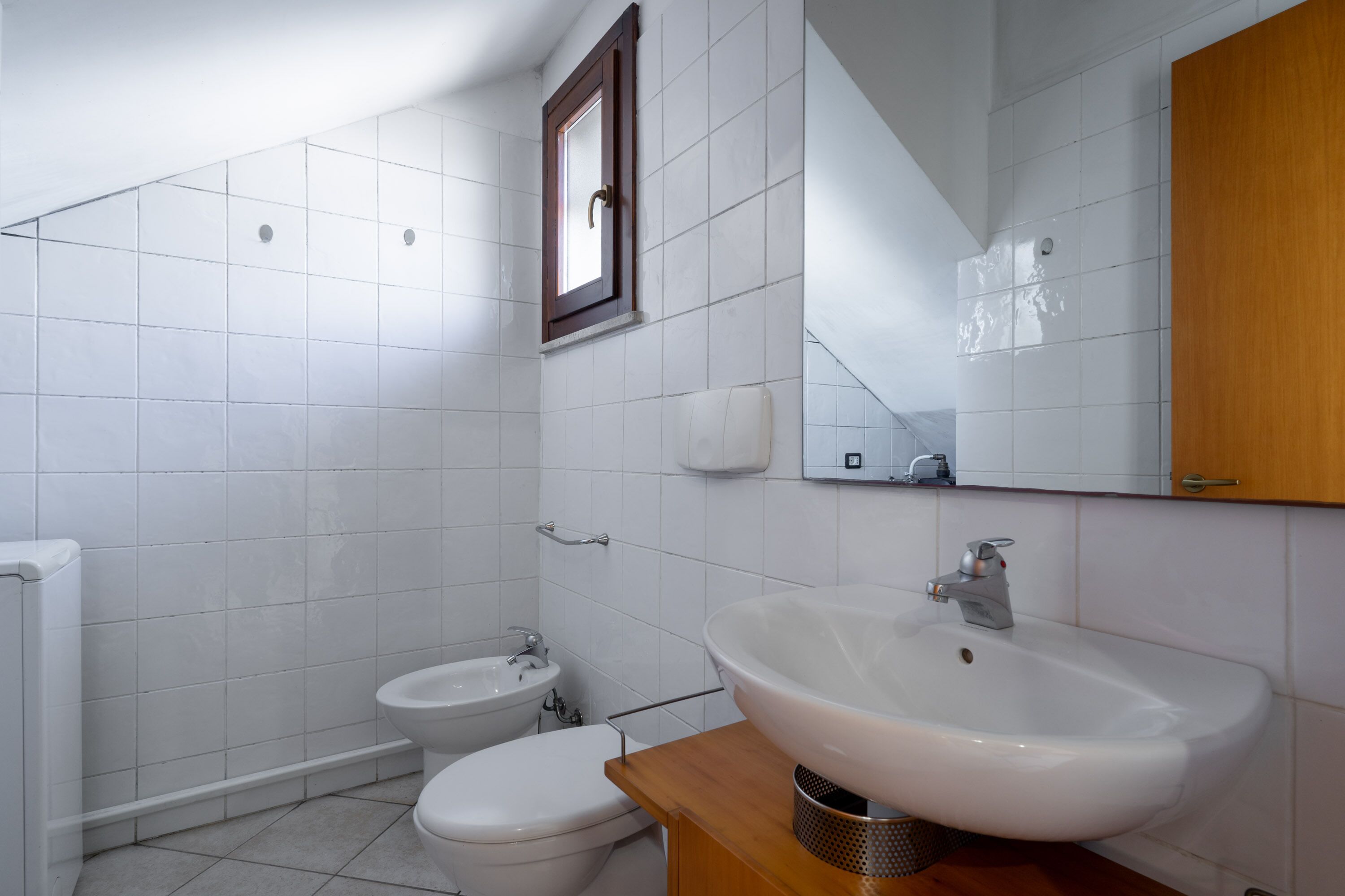 A bathroom with a large white sink, a toilet, and a bidet.