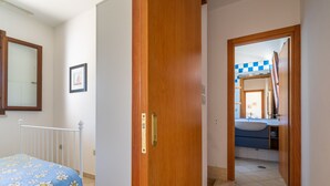 A bedroom with a bed, a wooden door, and a bathroom visible through an open door. - 3441 Villa Selvaggia by Barbarhouse (Nardò)
