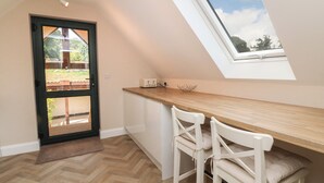 A modern kitchen with a wooden countertop, white chairs, and a skylight. - Spicery Barn Loft (Exeter)