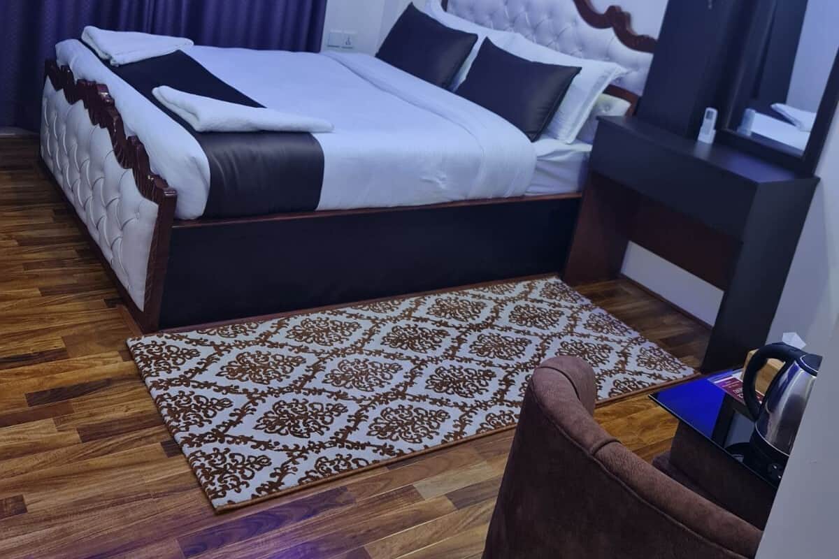 Habitación de hotel con cama, escritorio, silla, alfombra estampada y equipo de aire acondicionado.