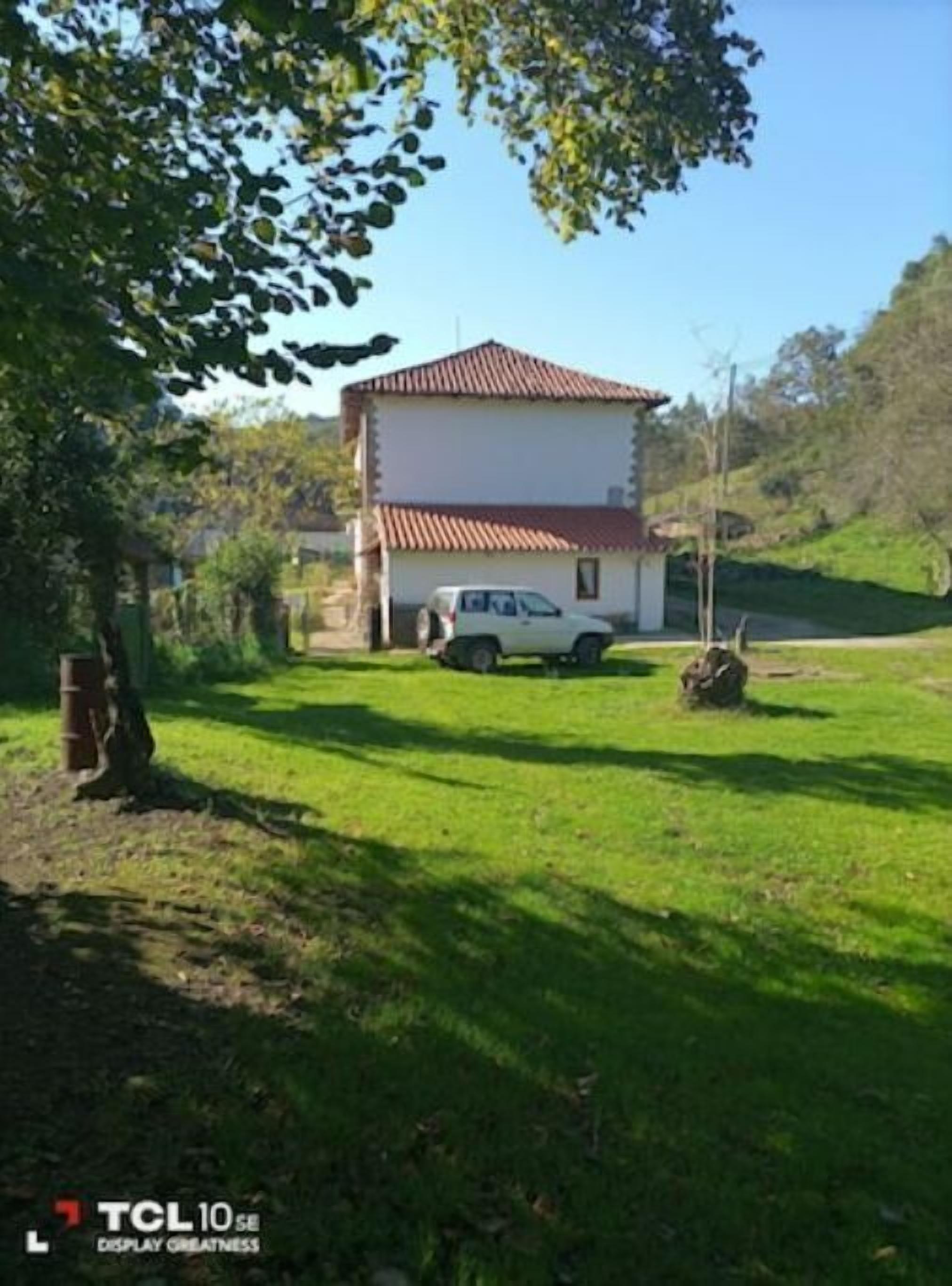 A two-story house with a red-tiled roof, a white car parked in the driveway, and a grassy yard.