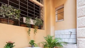 A small outdoor area with a white table, potted plants, and a window with metal bars. - Central and cozy loft with courtyard (Bologna)