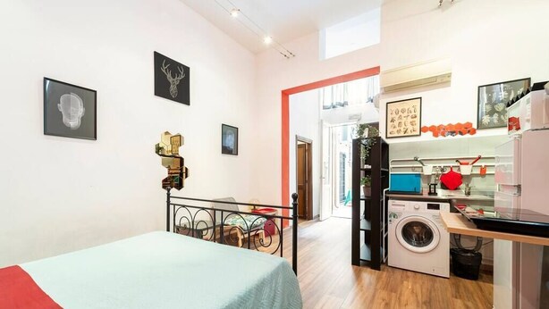 A compact room with a bed, a washing machine, and a kitchenette. - Central and cozy loft with courtyard (Bologna)