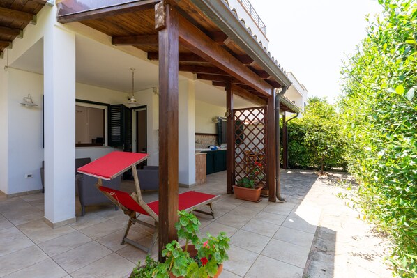Un espace extérieur abrité, doté d’une table et de chaises, d’une pergola en bois et de plantes en pot.
