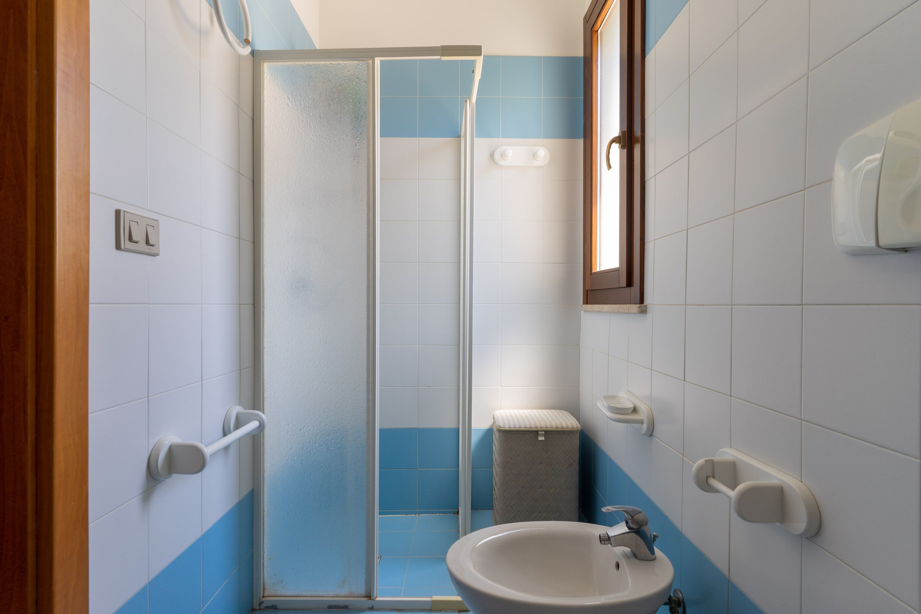 A bathroom with a glass shower enclosure, a sink, and a toilet.