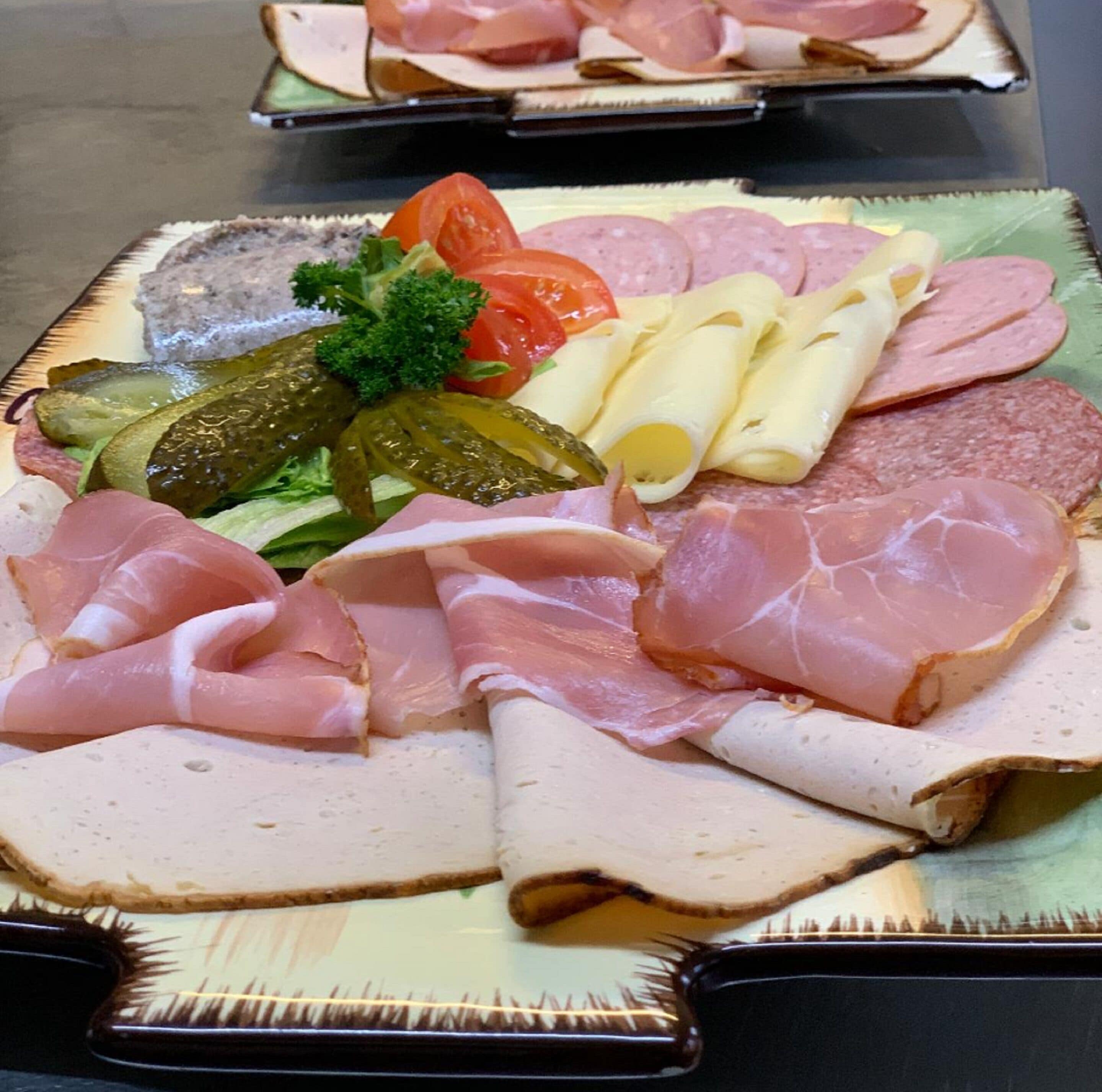 Una tabla de embutidos con diversos tipos de carne, quesos y pepinillos.