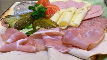 Una tabla de embutidos con diversos tipos de carne, quesos y pepinillos.