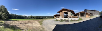 A rustic wooden building with a porch, surrounded by a gravel driveway and a dirt path.