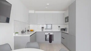Una cocina moderna con gabinetes grises, una encimera blanca y un microondas integrado.