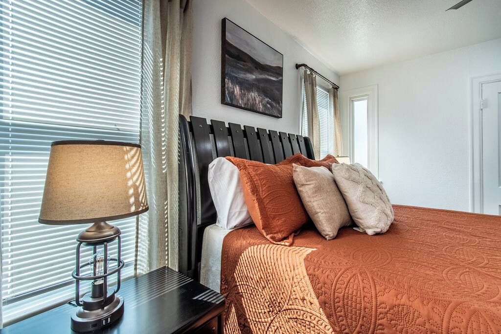 A neatly made bed with a patterned bedspread, a bedside lamp, and a framed picture on the wall.
