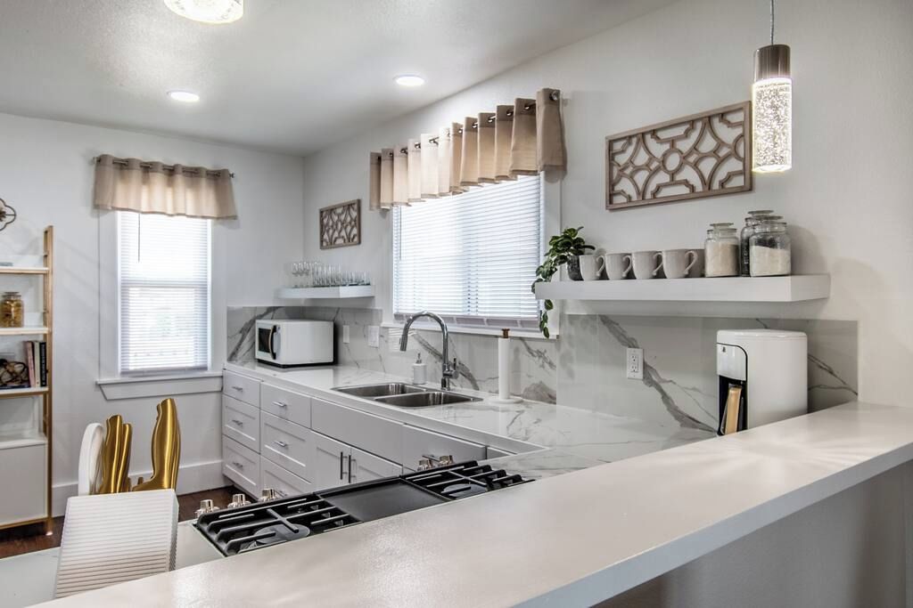 A modern kitchen with a central island, a built-in microwave, and a coffee machine.