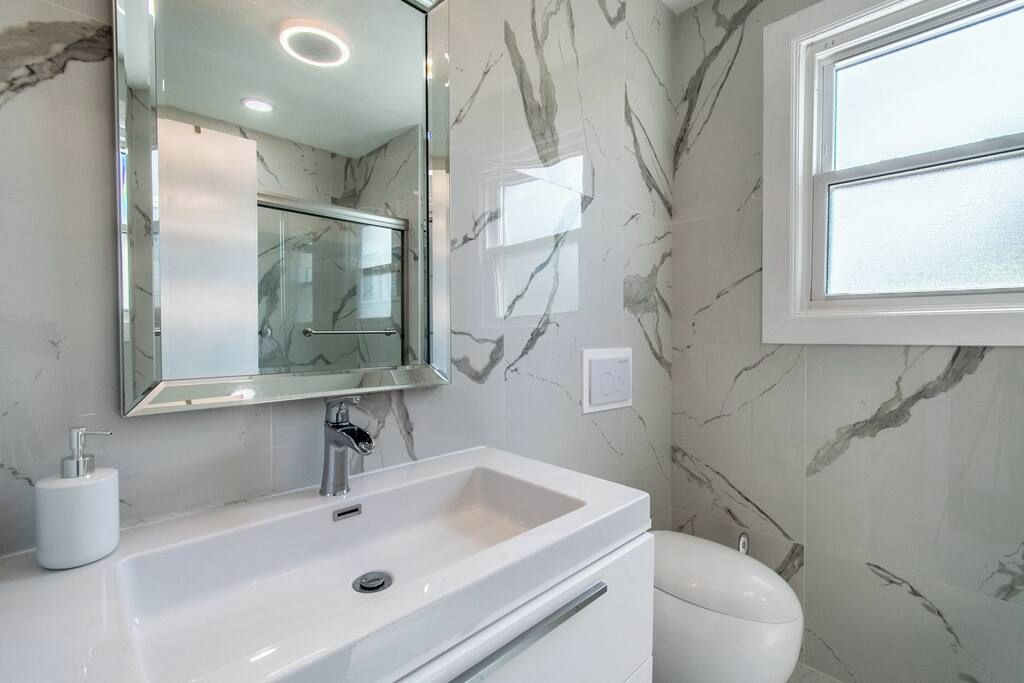 A bathroom with a white sink, a mirror, and a toilet.