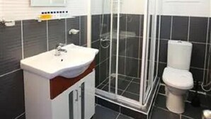A bathroom with a white sink, a glass-enclosed shower, and a toilet. - Arya Hotel Karaburun (Karaburun)