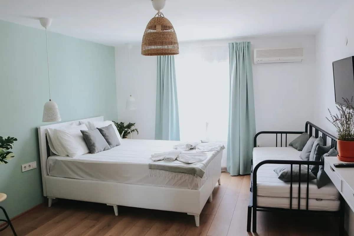 A bedroom with a bed, bedside tables, a desk, and a television.