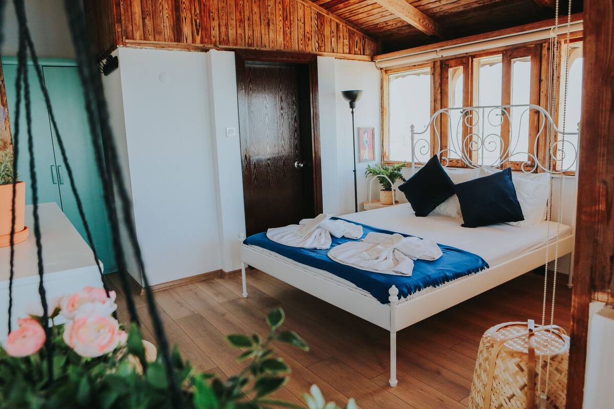 A bedroom with a bed, wooden ceiling, and a window.