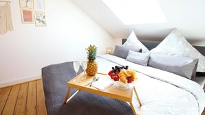 A bedroom with a bed, a bedside table with breakfast items, a macrame wall hanging, and framed quotes on the wall. - Boho-artstudio: Schicke Designer-wohnung mit Workspace +zentral+wifi+alexa+ (Duisburg)
