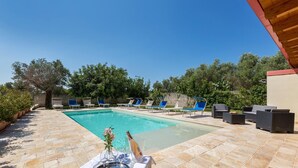 Ein Schwimmbecken mit Liegestühlen und einem Tisch mit Flasche und Blumen.