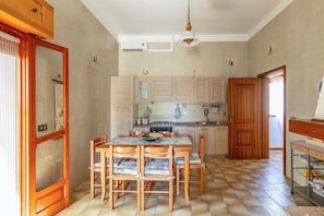 Una cocina con armarios de madera, una mesa de comedor con sillas y una lámpara colgante.