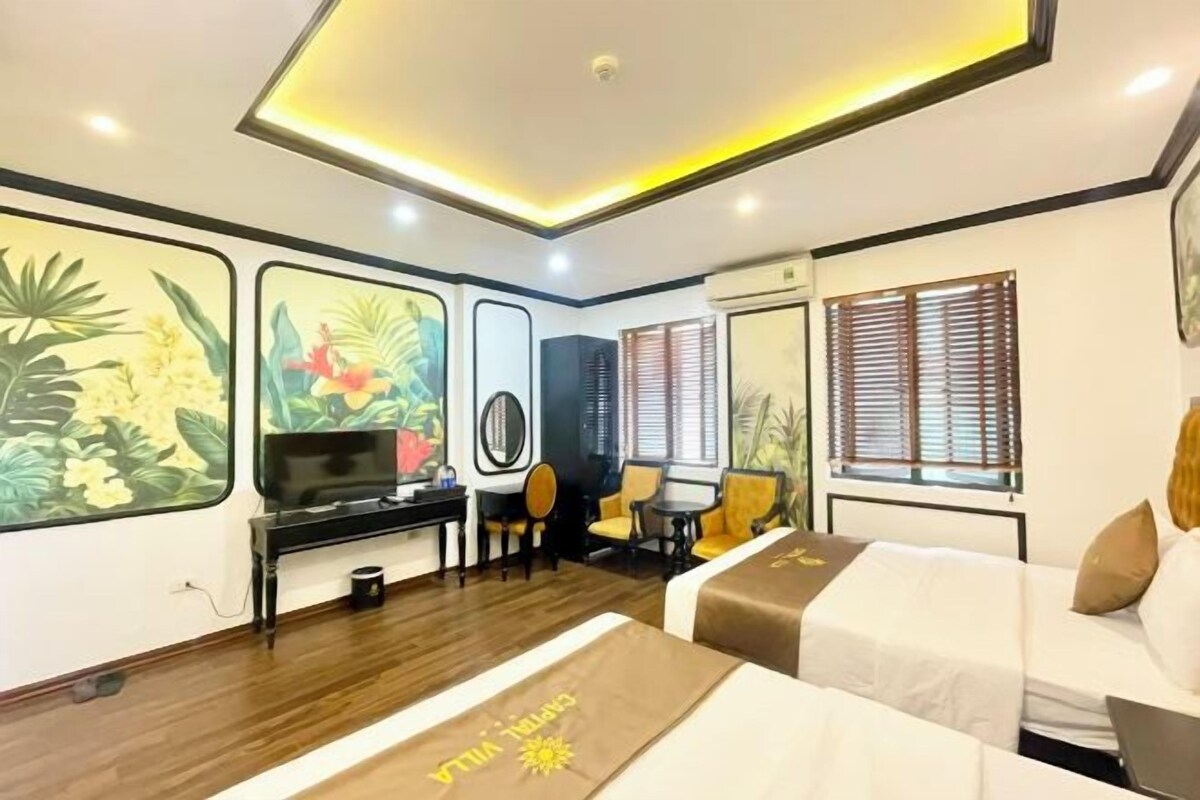 A hotel room with a bed, a desk, a TV, and a seating area.