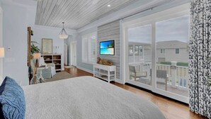 Une chambre spacieuse avec un grand lit, une télévision et un balcon offrant une vue sur la plage.