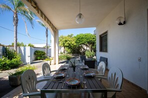 An outdoor dining area with a wooden table set for four, surrounded by white chairs. - 3539 Villetta dei Mirti by Barbarhouse (Nardò)