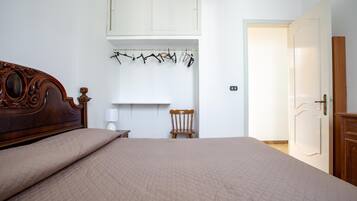 Quarto com cama grande, cabeceira de madeira, cadeira, cabideiro e guarda-roupa.