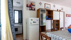 Eine kleine Küche mit Kühlschrank, Herd und offenen Schränken.