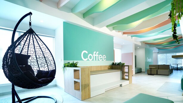 A modern coffee shop with a hanging chair, a reception desk, and a wall labeled "Coffee". - Truliv Olympus Elite (Chennai)