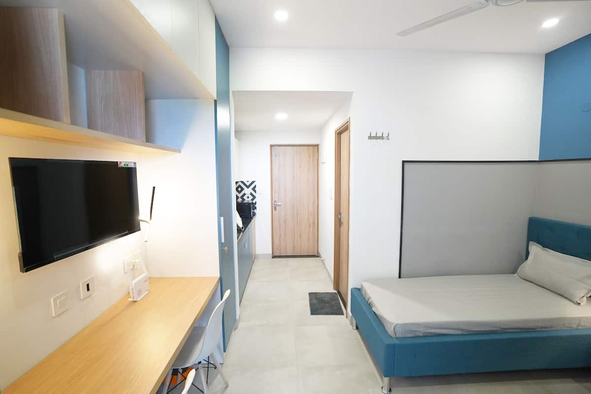 Quarto moderno com cama, escrivaninha e televisão.