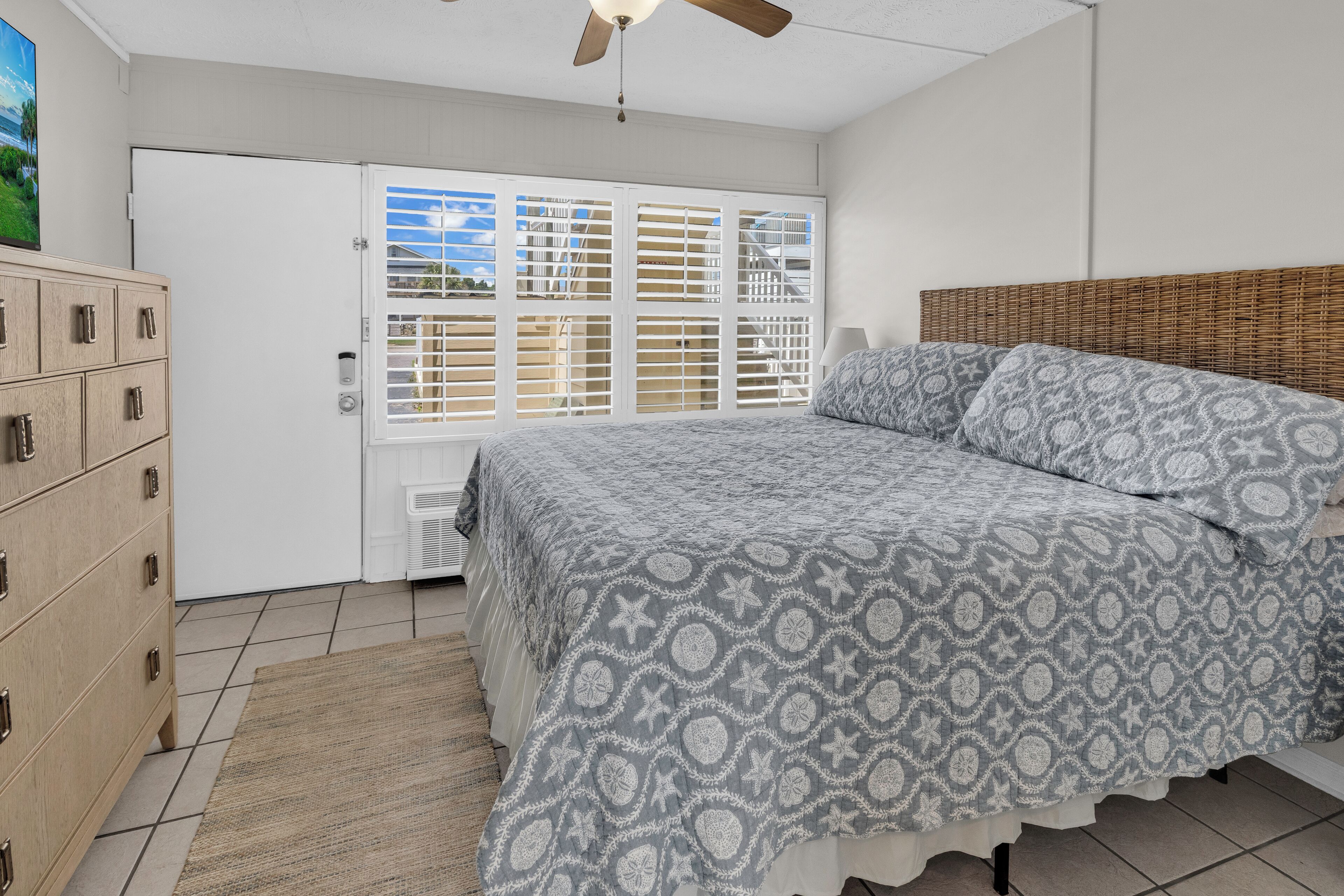 A bedroom with a bed, a dresser, a ceiling fan, and a window with blinds.