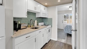 A kitchen with white cabinets, a microwave, a stove, and a sink. - Seaside Elegance Your Coastal Getaway (North Myrtle Beach)