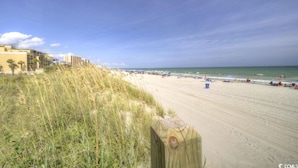 A beach with a wooden fence, beach umbrellas, and a clear sky. - Seaside Elegance Your Coastal Getaway (North Myrtle Beach)