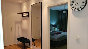 A bedroom with a large mirror, a bedside table, and a bed.